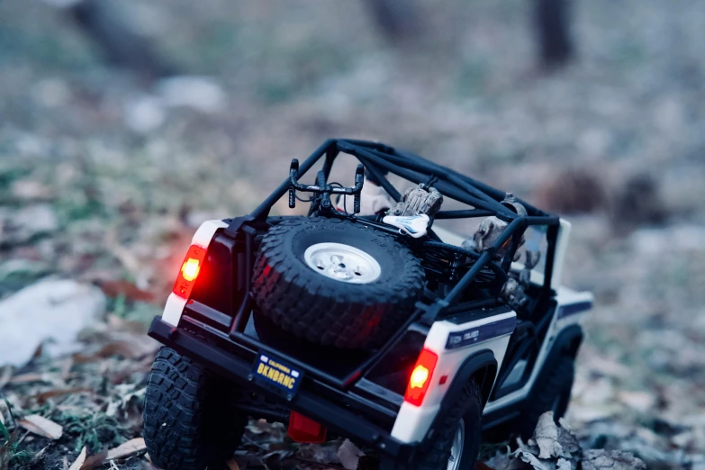 a toy jeep that is sitting on the ground, by Adam Marczyński, unsplash, photorealism, rear lighting, led, mahindra thar, leds