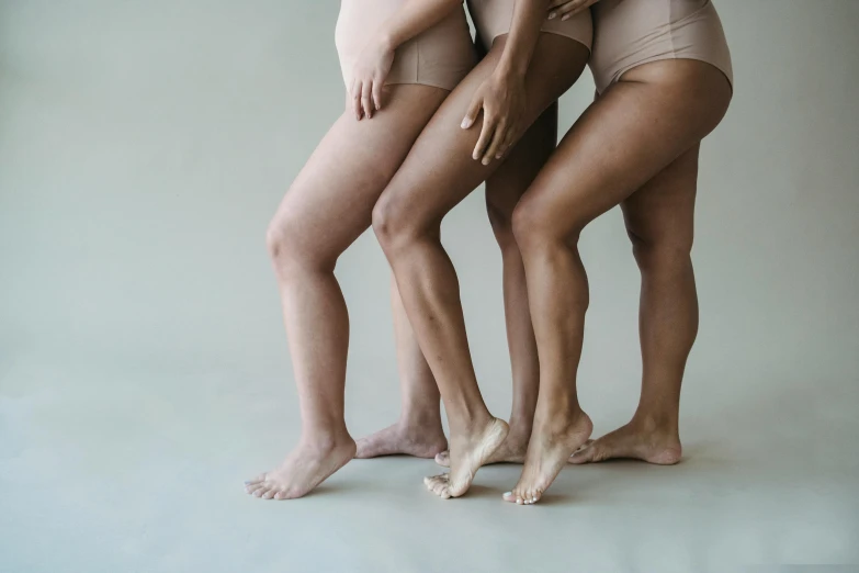 a group of three women standing next to each other, inspired by Vanessa Beecroft, trending on unsplash, thighs thighs thighs thighs, beige cream natural muted tones, piled around, wearing leotard