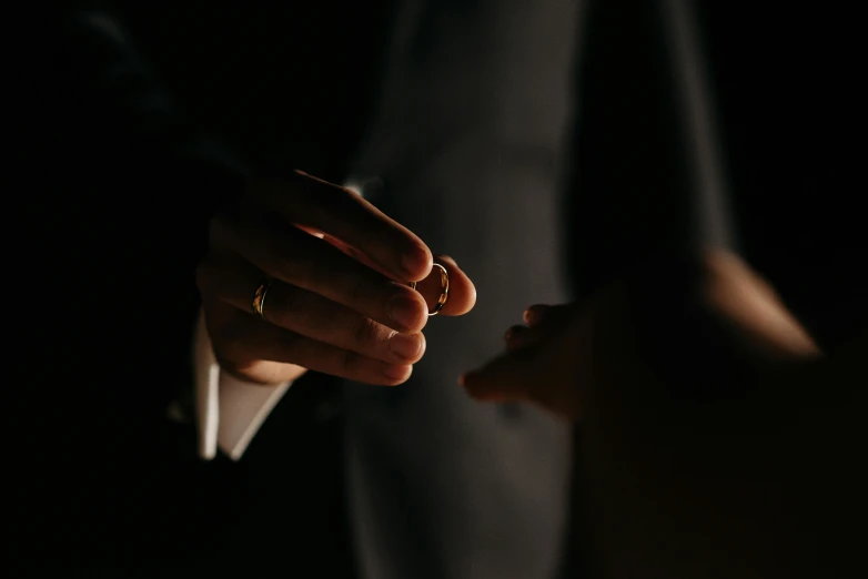 a close up of a person holding something in their hand, pexels contest winner, romanticism, men in tuxedos, ring lit, wearing simple robes, private moment