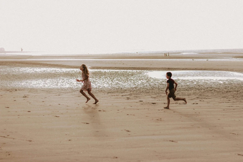 a couple of kids playing with a frisbee on a beach, an album cover, by Arabella Rankin, pexels contest winner, people running, long distance photo, on a canva, 10k