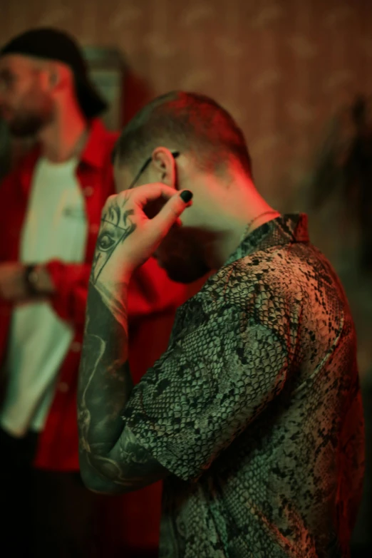 a man holding a cell phone to his ear, a tattoo, inspired by Elsa Bleda, trending on pexels, red room, praying with tobacco, undercut haircut, dj at a party