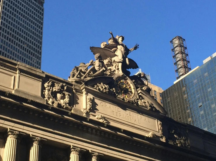 a statue on top of a building in a city, train station, met gala, intricate stone carvings, avatar image