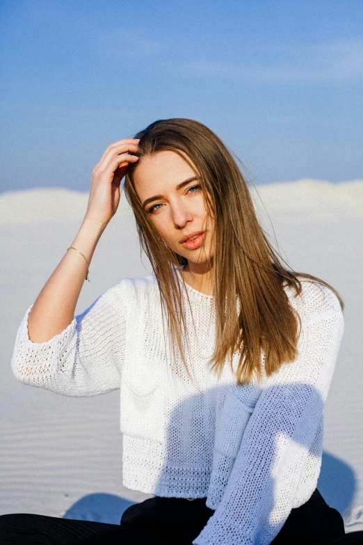 a beautiful young woman sitting on top of a sandy beach, by Julia Pishtar, trending on unsplash, minimalism, straight stiff dry damaged hair, wearing a white sweater, standing in desert, crisp face
