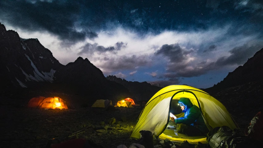 a person sitting inside of a tent at night, pexels contest winner, under a dark cloudy sky, adventure gear, avatar image, tents