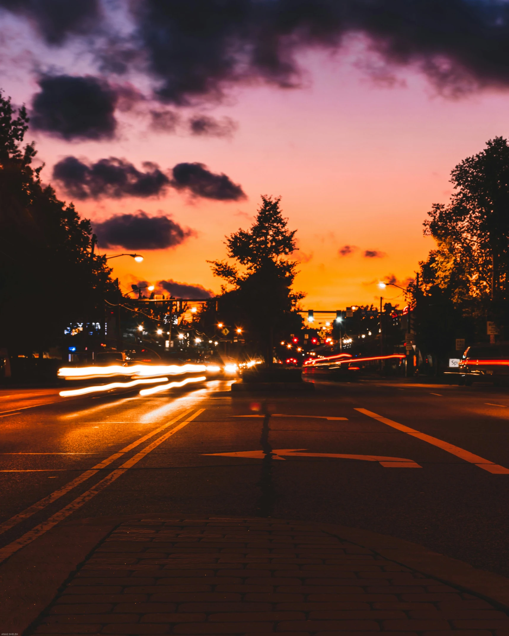 a city street filled with lots of traffic at night, an album cover, unsplash contest winner, sunset!, lgbtq, beautiful small town, city lights made of lush trees