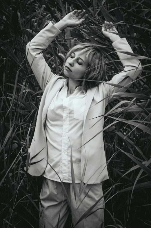 a black and white photo of a woman standing in tall grass, inspired by Leila Faithfull, wearing white shirt, joel fletcher, various pose, zoe kazan