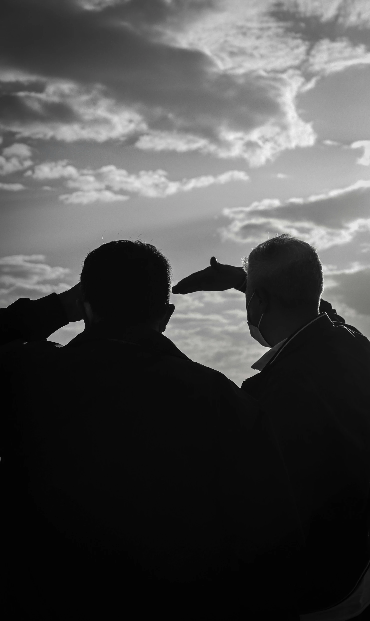 a couple of men standing next to each other, a black and white photo, by Ian Fairweather, unsplash, symbolism, saluting, looking off into the sunset, spying discretly, behind the scenes