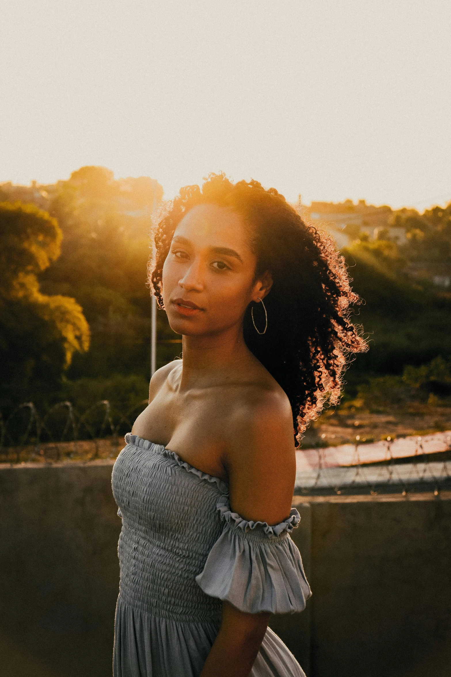 a woman standing in front of a body of water, an album cover, pexels contest winner, renaissance, ashteroth, sundown golden hour, headshot profile picture, on a rooftop