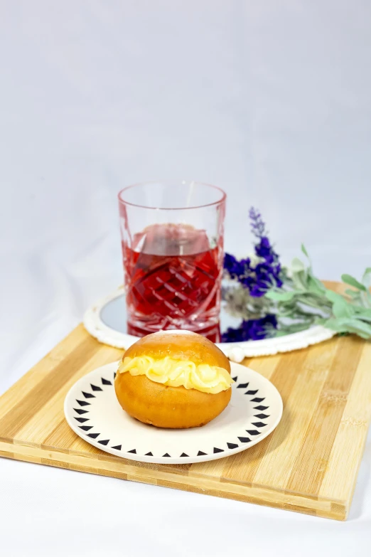 a white plate topped with a pastry next to a glass of water, bao phan, purple themed, lemonade, high-quality photo