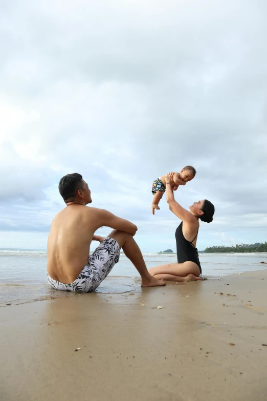 a man playing with a baby on the beach, a picture, by Jessie Algie, unsplash, renaissance, an indonesian family portrait, square, portrait of family of three, haida