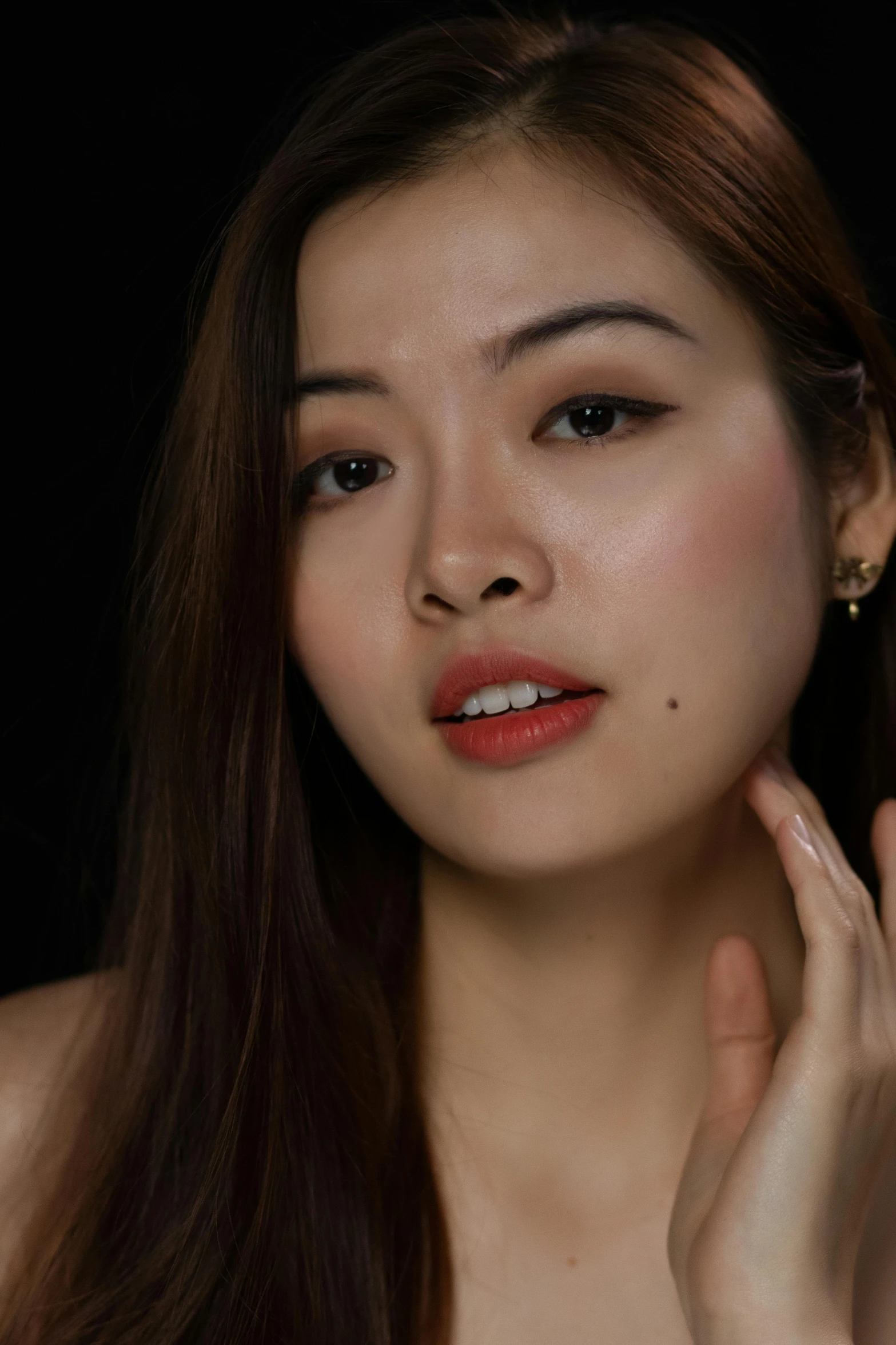 a woman posing for a picture in front of a black background, inspired by Wen Jia, trending on pexels, photorealism, skincare, square face, shot at golden hour, hand on her chin