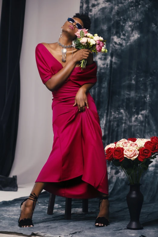 a woman in a red dress holding a bouquet of flowers, inspired by Carrie Mae Weems, instagram, romanticism, flowing pink-colored silk, circa 1992, wearing an evening gown, backdrop