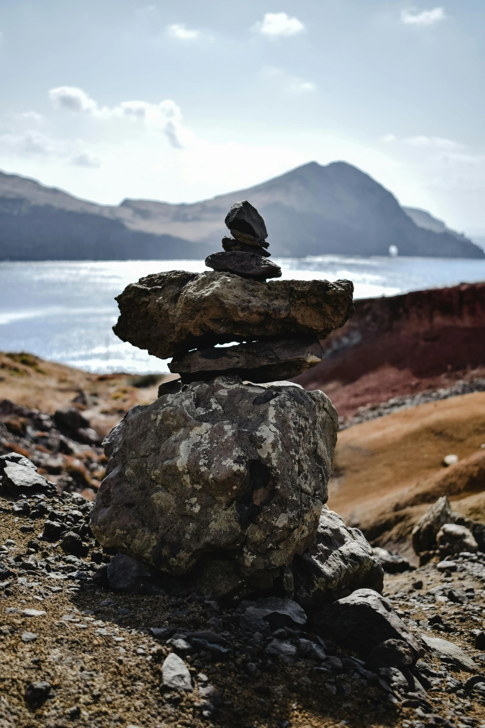 a pile of rocks sitting on top of a rocky hillside, a statue, azores, rocky lake shore, 2019 trending photo, slate