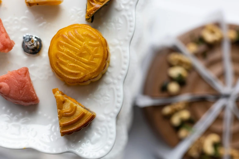 a white plate topped with different types of desserts, inspired by Richmond Barthé, pexels, hurufiyya, hand carved brown resin, chinese heritage, 3 - piece, brown and gold