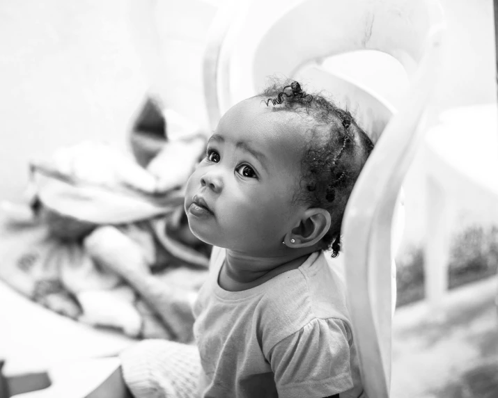 a little girl sitting on top of a bed, a black and white photo, by Daniel Gelon, pexels contest winner, sitting in his highchair, light skinned african young girl, messy eater, closeup portrait shot