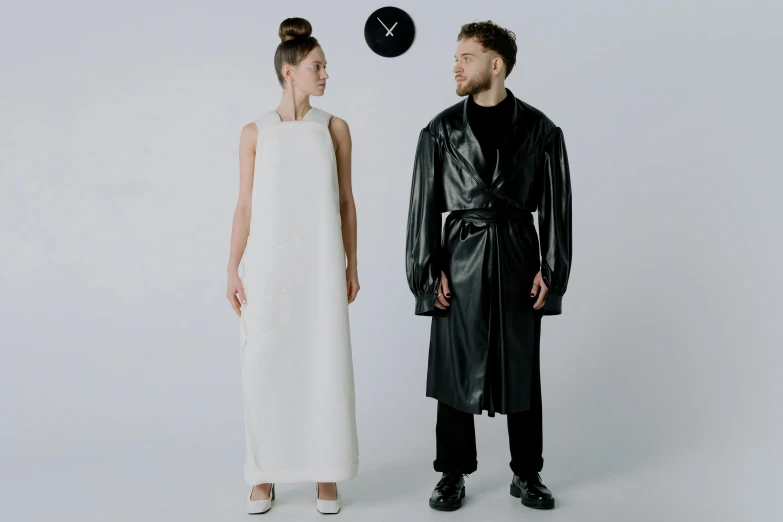 a man and a woman standing next to each other, an album cover, inspired by Jonas De Ro, bauhaus, black leather garment, wearing a long dress, lunar time, stable diffusion ai as a human