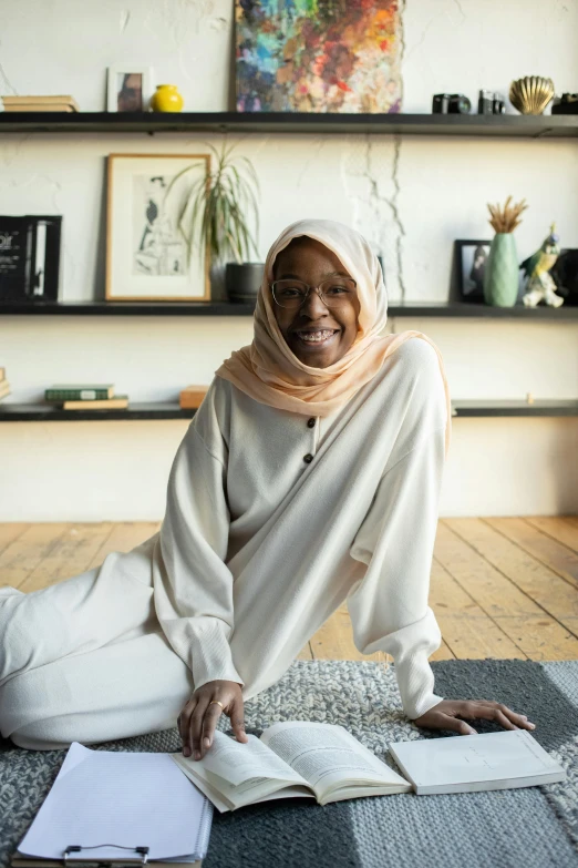 a woman sitting on the floor reading a book, inspired by Maryam Hashemi, hurufiyya, wearing a white sweater, jemal shabazz, satisfied pose, swedish