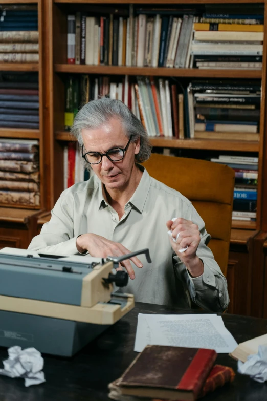 a man sitting at a desk typing on a typewriter, george miller, teaching, promo image, kiki smith
