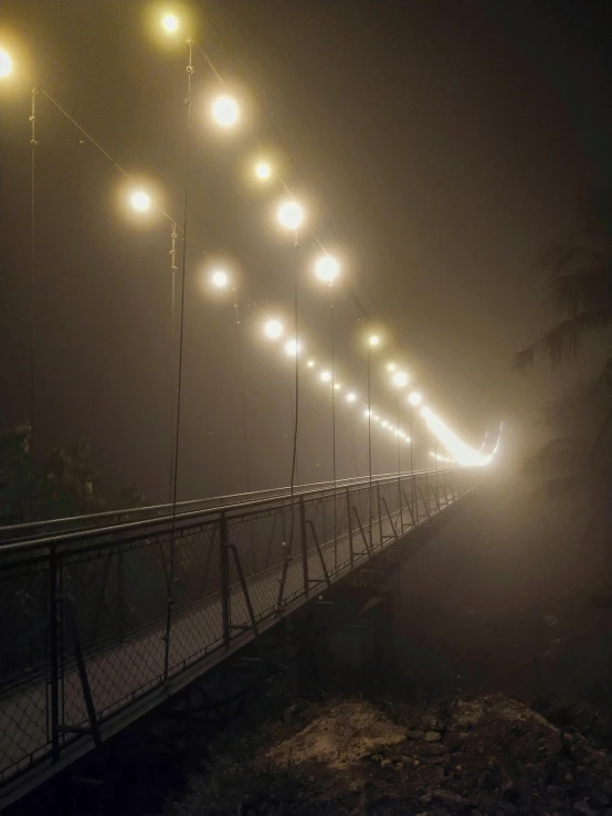 a long suspension bridge on a foggy night, by Jessie Algie, 2022 photograph, todd hido, ilustration, atmospheric lighting - n 9