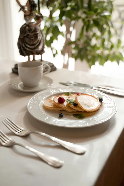 a close up of a plate of food on a table, inspired by Rudolf von Alt, art nouveau, pancakes, white, cozy setting, elegant