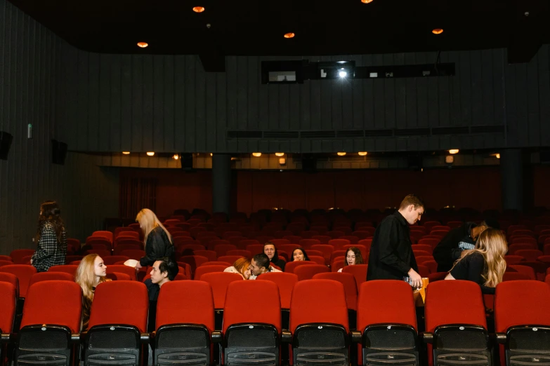 a group of people sitting in rows of red chairs, russian cinema, jovana rikalo, high quality photo, movie footage