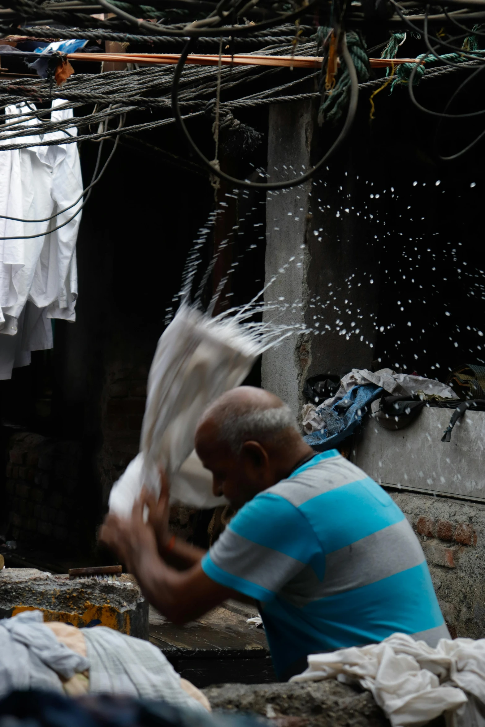 a man standing in front of a pile of clothes, a silk screen, pexels contest winner, splashing water, calcutta, real life photo of a syrian man, shower cap