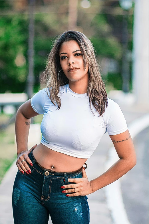 a woman standing on the side of a road with her hands on her hips, by Samuel Silva, instagram, with ripped crop t - shirt, headshot, brazilian, alanis guillen