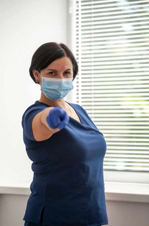 a woman wearing a surgical mask and gloves, a picture, by Robert Medley, shutterstock, happening, holding a staff, fight pose, ots shot, press photos