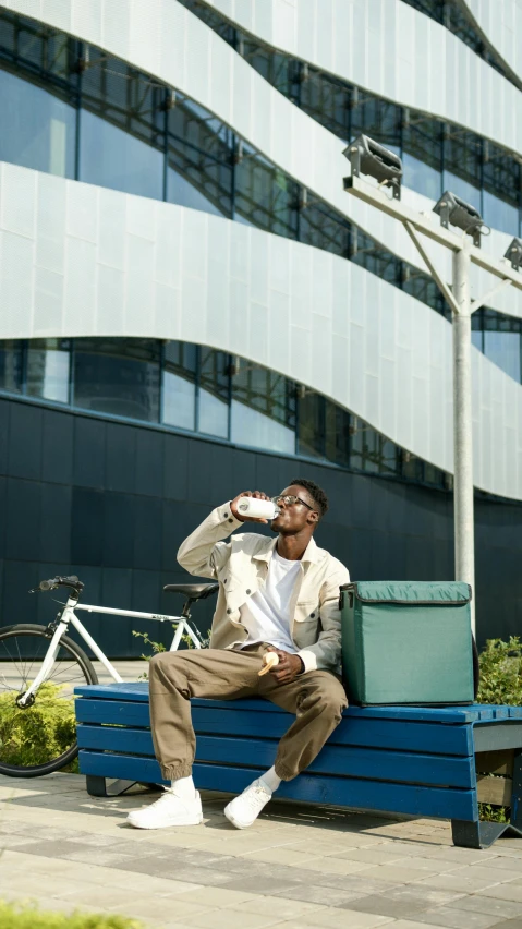 a man sitting on a bench talking on a cell phone, by Andries Stock, pexels contest winner, happening, water to waste, milkman, sassy pose, sustainable materials