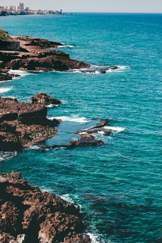 a large body of water next to a rocky shore, inspired by Elsa Bleda, pexels contest winner, les nabis, brown and cyan color scheme, puerto rico, concert, south african coast