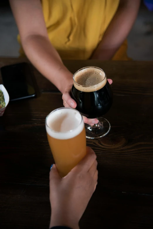 a couple of people holding glasses of beer, black and brown, back of hand on the table, subtle detailing, collaboration