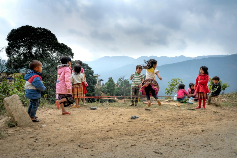 a group of children standing on top of a dirt field, pexels contest winner, happening, bhutan, swings, dancers, panoramic view of girl