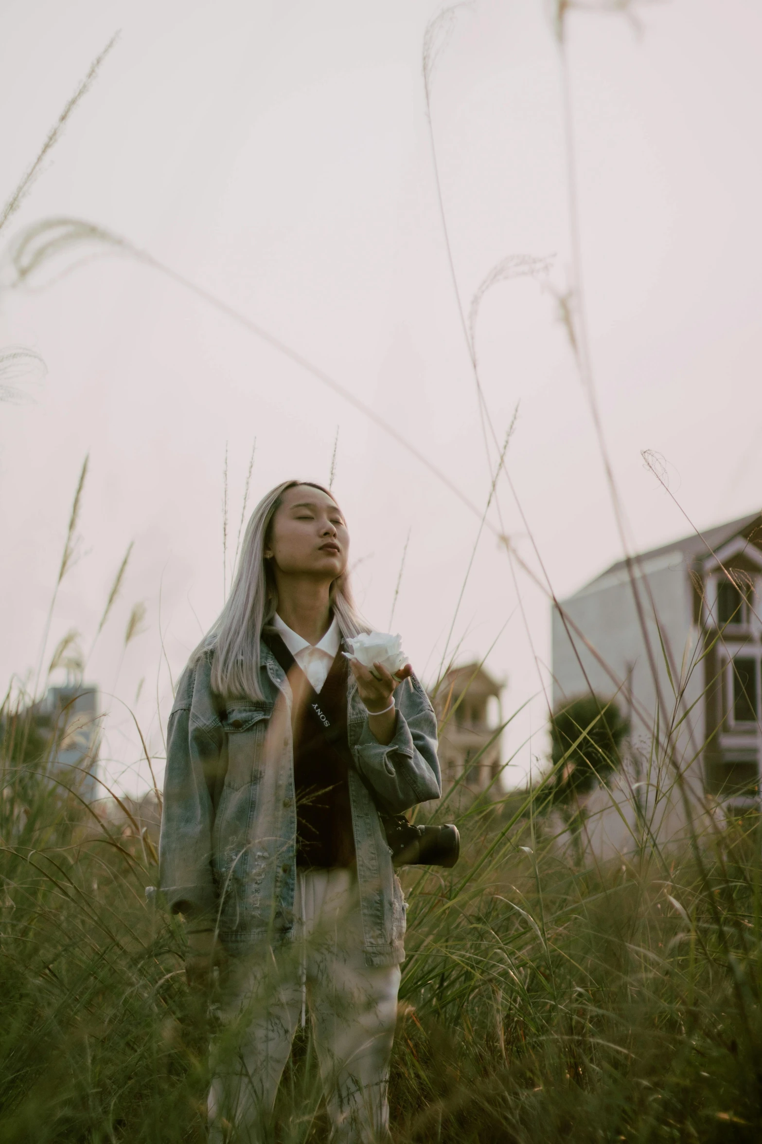 a woman standing in a field of tall grass, an album cover, by Mei Qing, unsplash contest winner, girl silver hair, walking through a suburb, low quality footage, full body potrait holding bottle