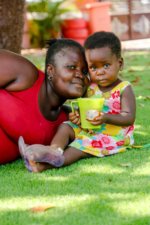 a woman and a child laying on the grass, by Ingrida Kadaka, pexels contest winner, dada, chocolate, babies in her lap, square, coloured