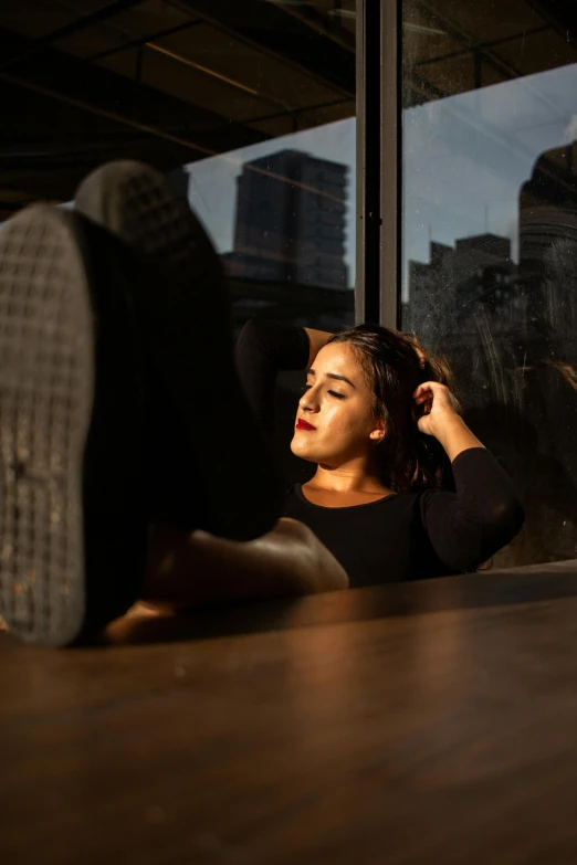 a woman laying on the floor in front of a window, inspired by Elsa Bleda, pexels contest winner, realism, backlit face, in a coffee shop, profile image, high soles