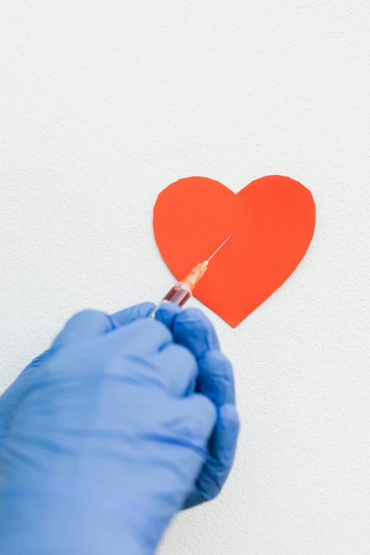 a person in blue gloves holding a red paper heart, by Julia Pishtar, trending on reddit, syringes, low quality photo, pulled apart, ilustration