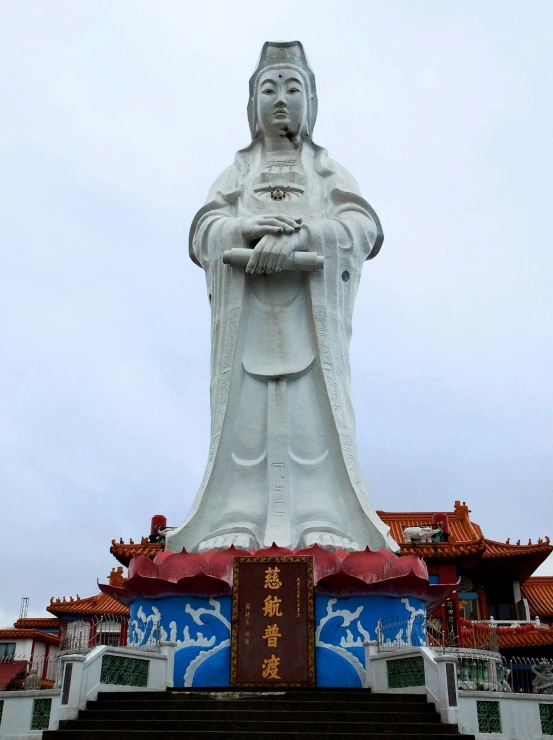 a statue of a woman standing in front of a building, inspired by Ju Lian, guanyin of the southern seas, 1km tall, puṣkaracūḍa, virgin mary