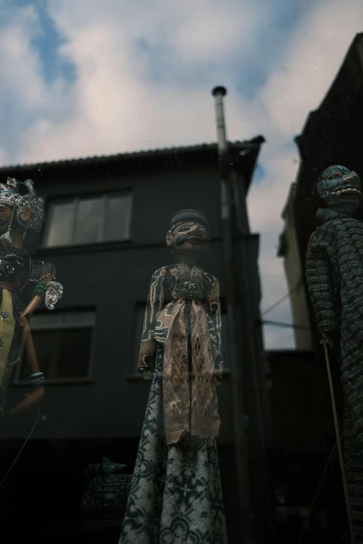 a group of mannequins in front of a building, by Attila Meszlenyi, afrofuturism, stopmotion, barong family, [ cinematic, slide show