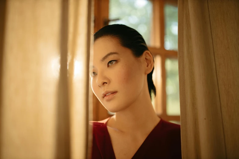 a close up of a woman looking out a window, pexels contest winner, shin hanga, lucy liu portrait, medium format. soft light, behind red curtains, instagram post