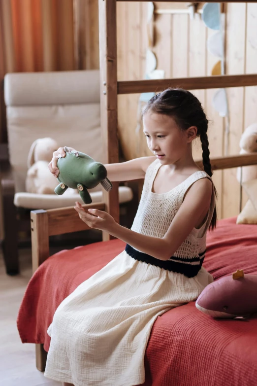 a little girl sitting on a bed holding a piggy bank, inspired by Elsa Beskow, pexels contest winner, wooden hippo, ( ( theatrical ) ), kids playing, soviet - era