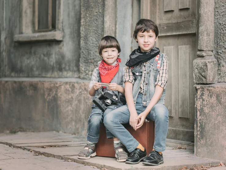 a couple of young boys sitting on top of a suitcase, by Lucia Peka, pexels contest winner, ukrainian, avatar image, on the sidewalk, denim