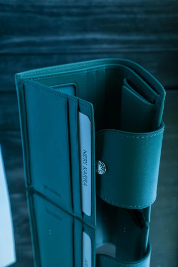 a close up of a wallet on a table, dark teal lighting, product display photograph, green and blue tones, detailed and soft