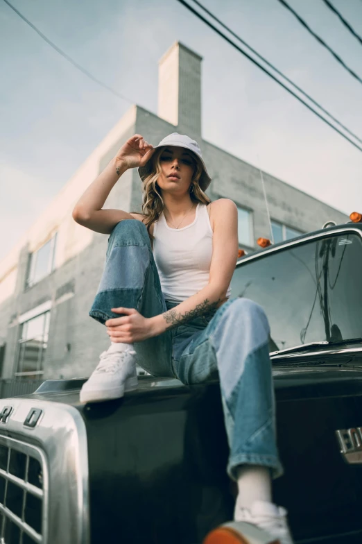 a woman sitting on the hood of a truck, inspired by Elsa Bleda, trending on pexels, white hat, baggy jeans, hollywood promotional image, official store photo