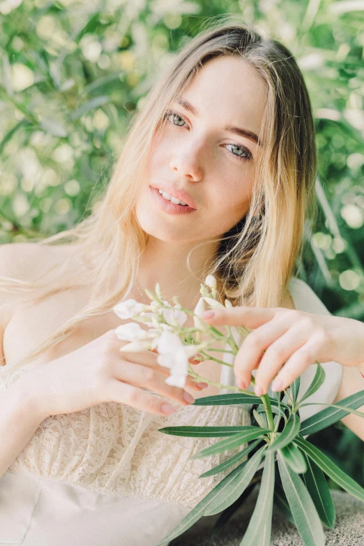 a woman holding a flower in front of her face, trending on unsplash, renaissance, portrait of kim petras, eucalyptus, synthetic bio skin, with long blond hair