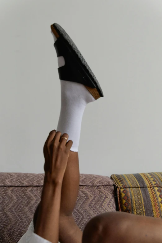 a person laying on a couch with their feet up, off - white collection, giant kicking foot, looking across the shoulder, layer upon layer