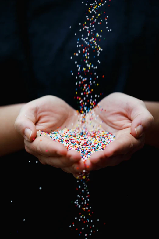 a person holding sprinkles in their hands, by Adam Chmielowski, pexels, kinetic pointillism, 500px, made of plastic, edible, colorful and dark