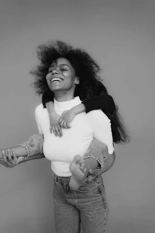 a black and white photo of a woman holding a child, a black and white photo, by Clifford Ross, pexels contest winner, sza, smiling playfully, arms extended, afro