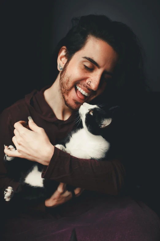 a man holding a black and white cat in his arms, trending on pexels, furry art, better known as amouranth, smiling playfully, post malone, miguel iglesias