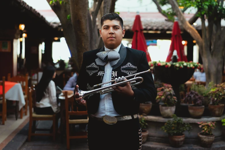 a man in a sombren holding a trumpet, by Gina Pellón, pexels contest winner, standing in a cantina, formal attire, los angelos, al fresco