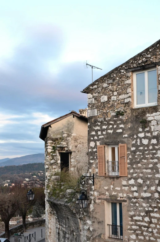 a couple of buildings that are next to each other, an album cover, inspired by Jean-Baptiste-Camille Corot, unsplash, renaissance, snowy apennines, old stone wall, early evening, shot from roofline